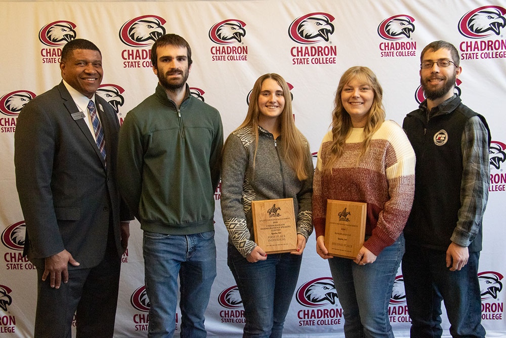 Five adults posing inside with awards