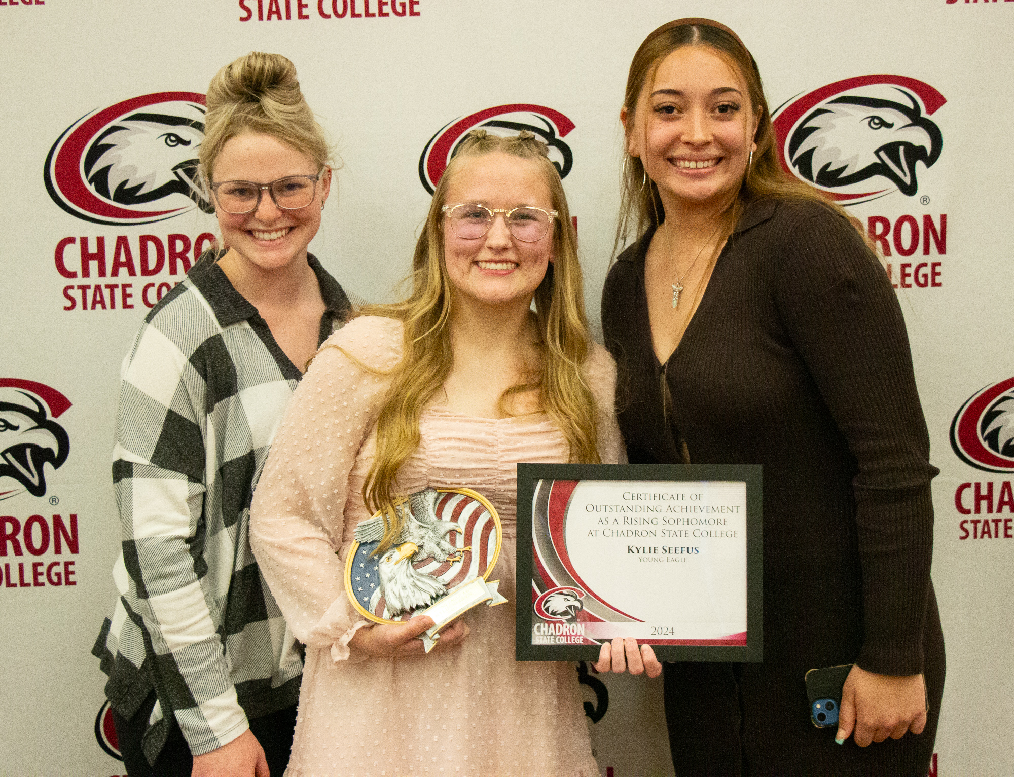 Three women posing with an award