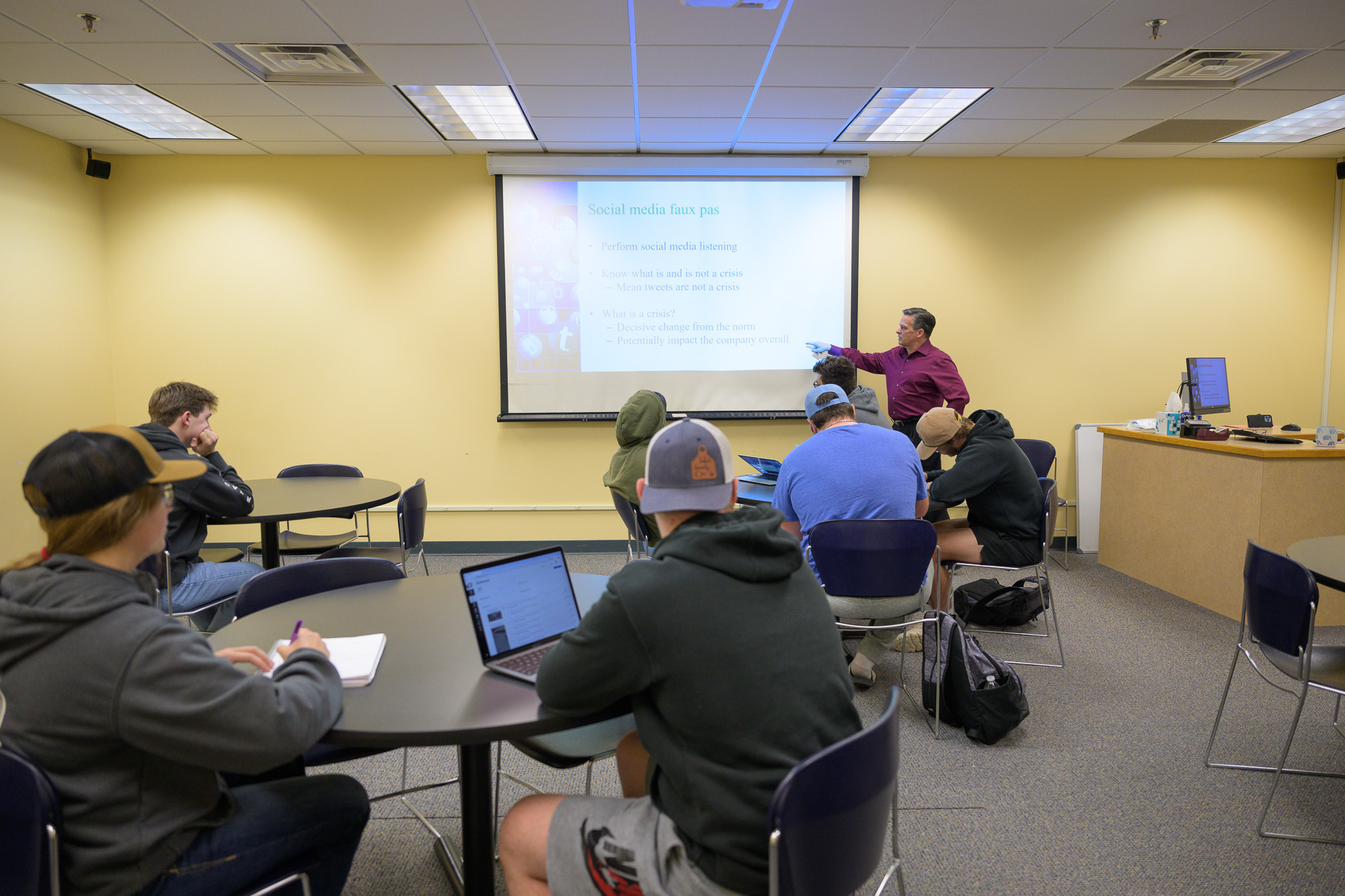 Male instructor showing students an image projected on a screen