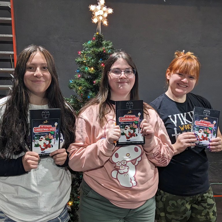 Three women posing by a Christmas tree