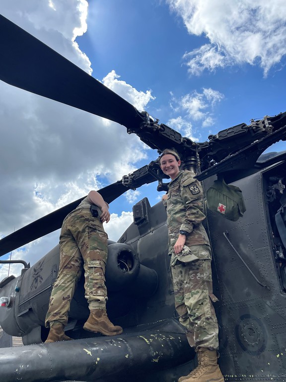 Woman in uniform standing under a helicopter