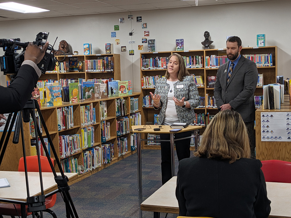 A male and a female speaking at a press release in a school