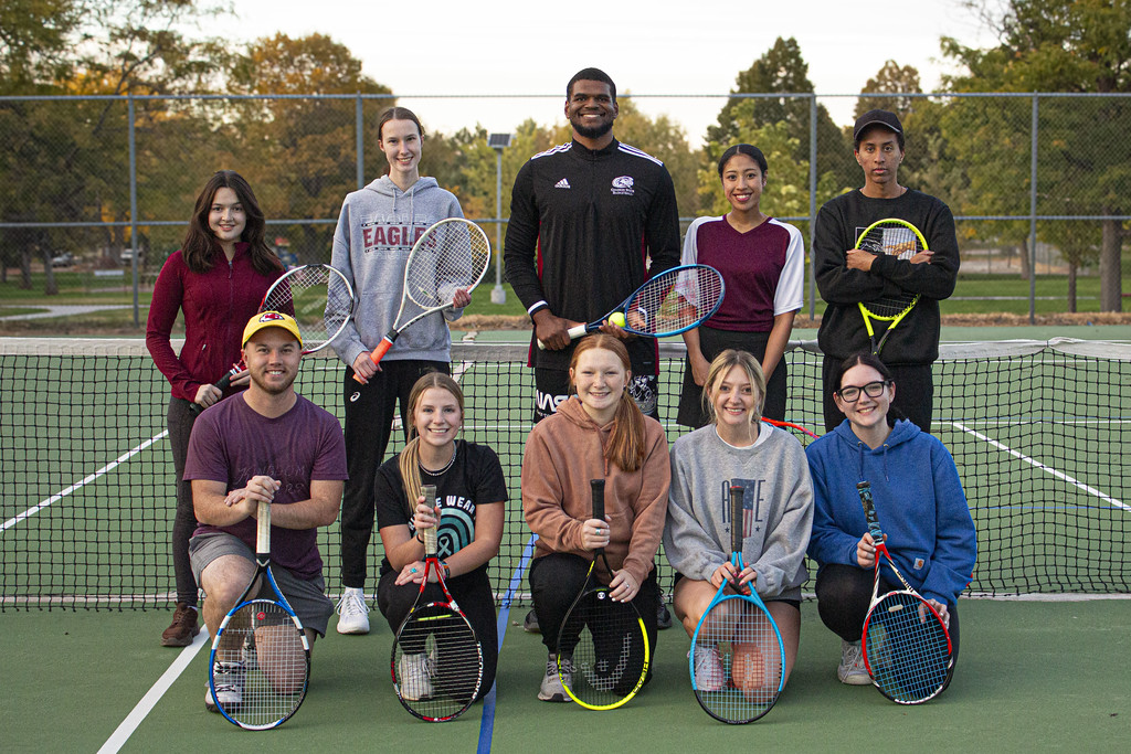 A group of college students posing on a tennis court