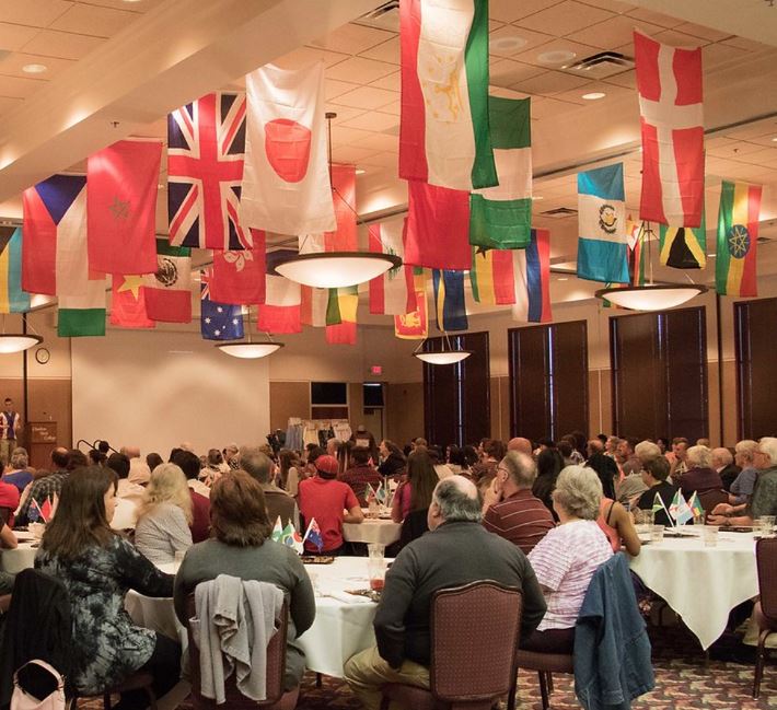 Crowd at dining tables with flags suspended from ceiling