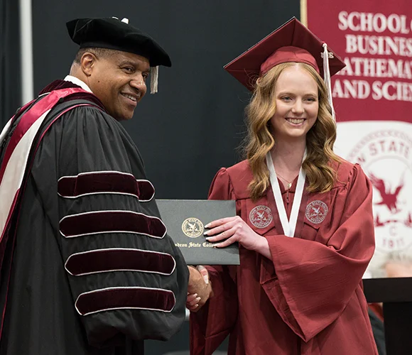 College president and graduate smiling