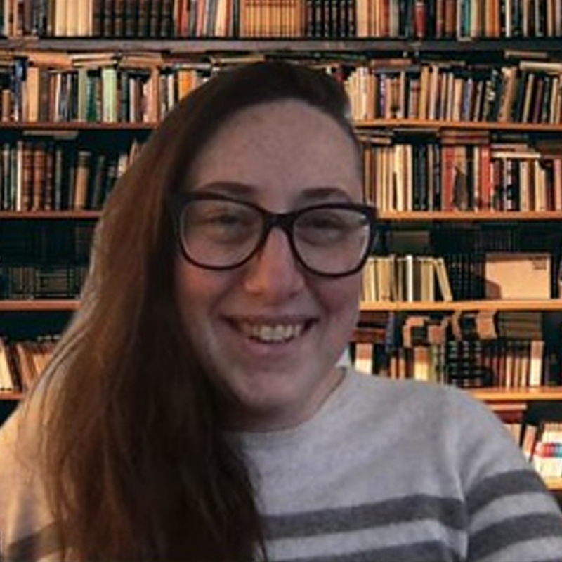 Screenshot of an instructor, in front of bookshelves, recording a video message.