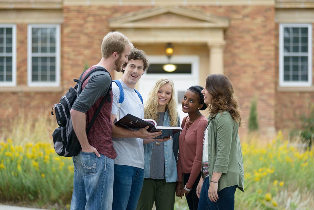 Five students discussing a section of a textbook in front of the Mari Sandoz High Plains Heritage Center